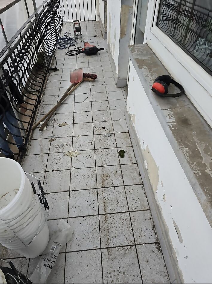 Derselbe Balkon vorher mit altem weißem Fliesenbelag und Werkzeug auf der Fläche