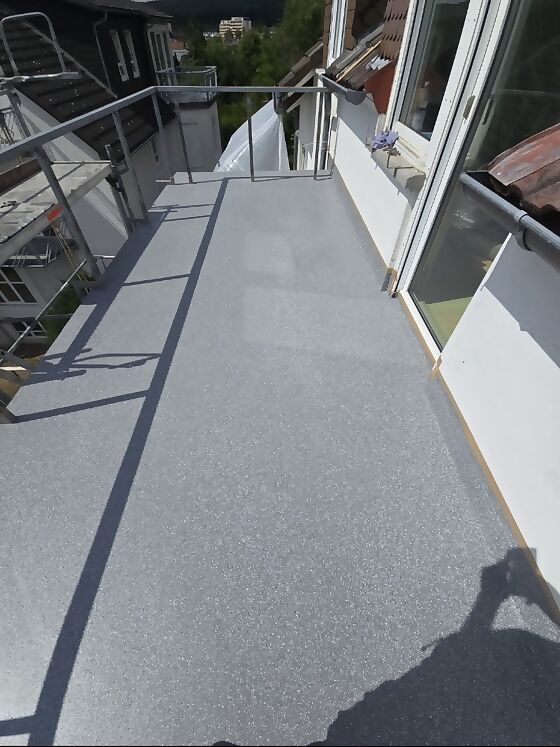 Fertig beschichteter Balkon mit rutschhemmender, eingestreuter Oberfläche in Grau