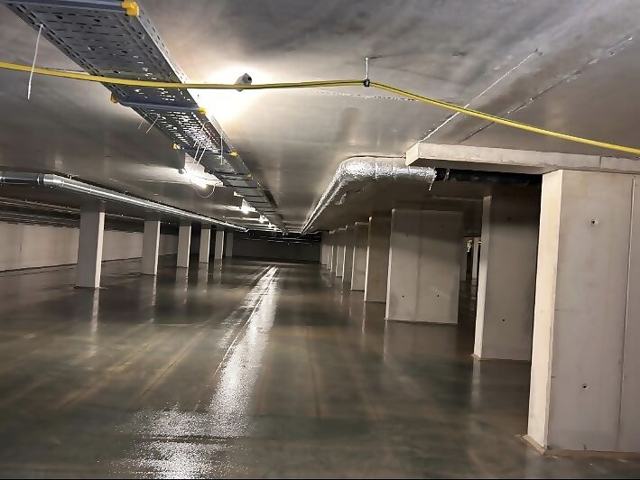 Lange Tiefgaragenfahrgasse mit beschichtetem Boden und Stützen