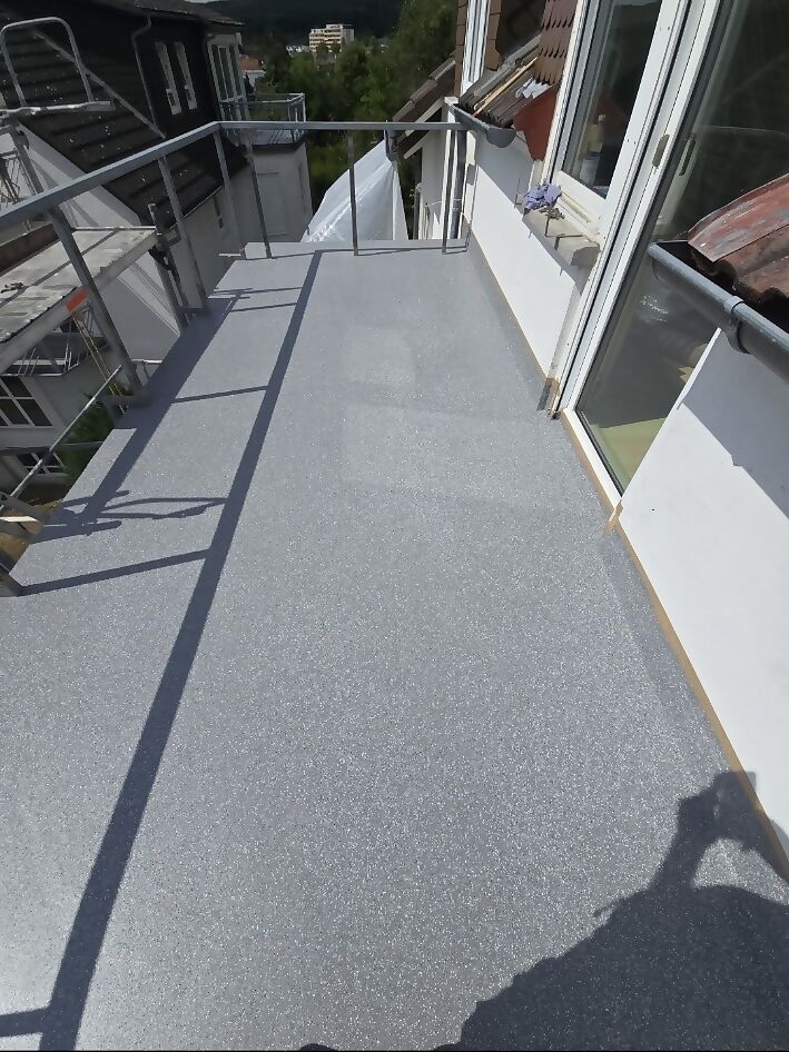 Dachterrasse nach der Sanierung mit durchgehend beschichteter, grau eingestreuter Oberfläche