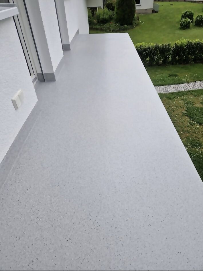 Terrasse nach der Beschichtung mit heller, fugenloser Oberfläche und Blick in den Garten